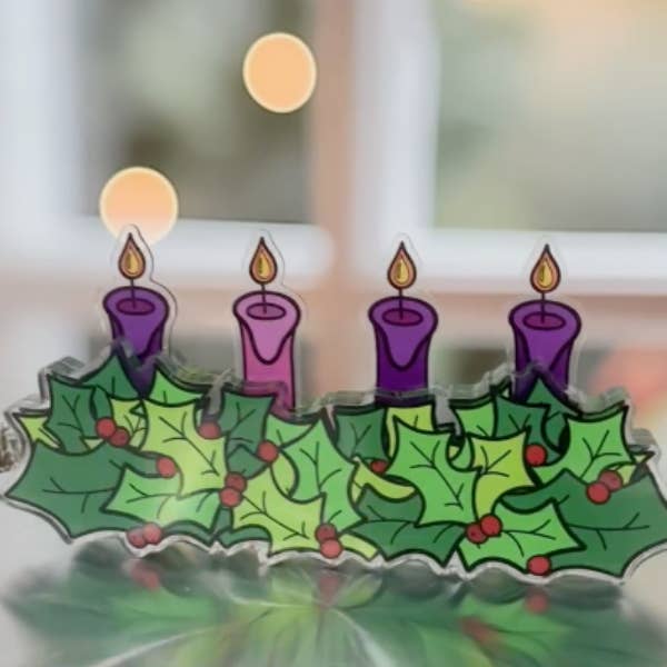 Decorative Advent wreath with holly leaves and purple candles on a reflective surface.